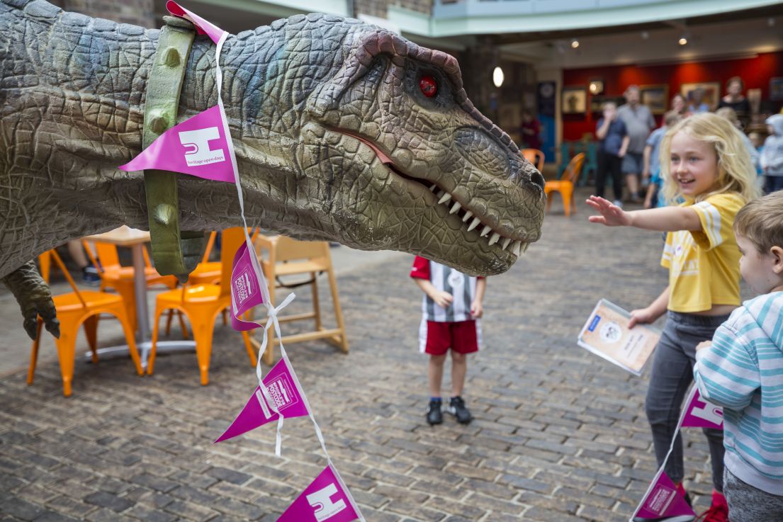 An animatronic dinosaur with HODs pink bunting entertaining children. 